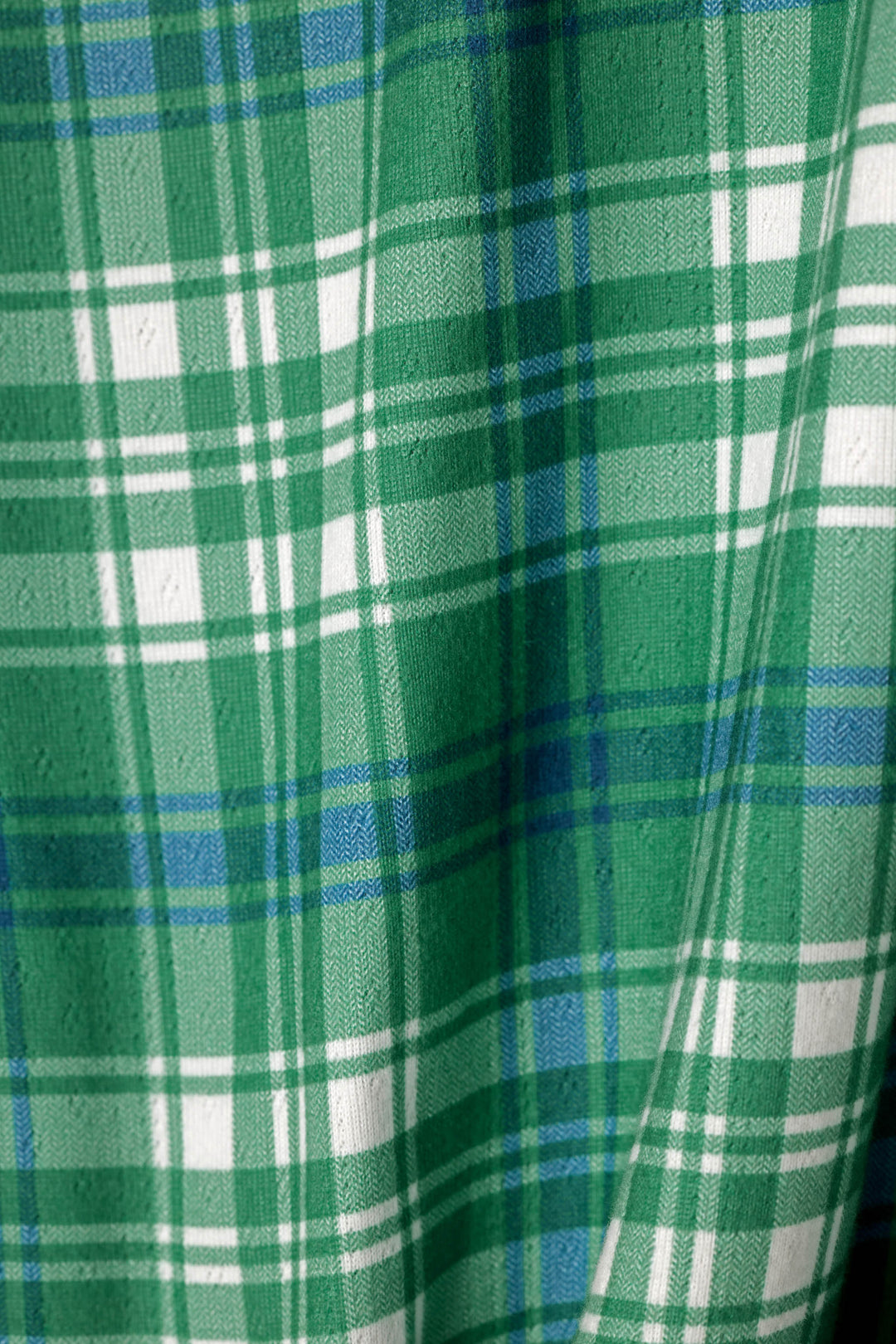 A close-up of a green plaid fabric with white and blue stripes, showing a soft woven texture.