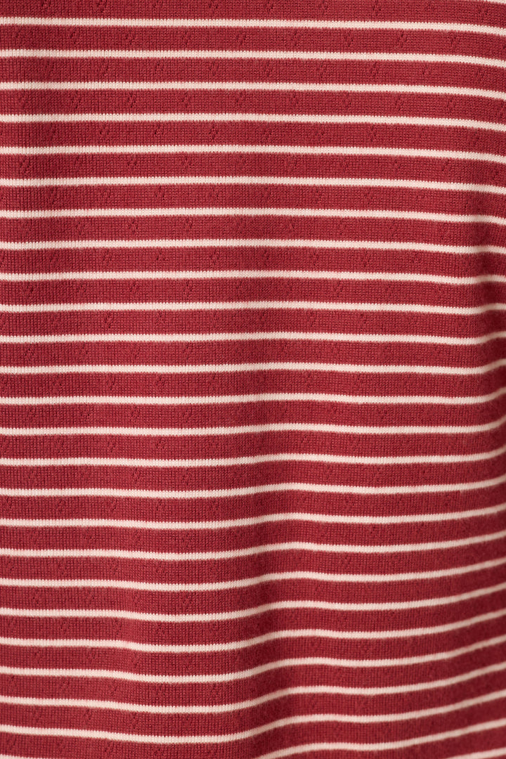 A close-up of a red knit fabric with thin, evenly spaced horizontal white stripes.