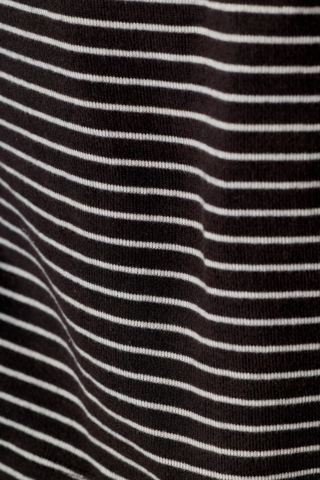 A close-up of a black knit fabric with thin, evenly spaced horizontal white stripes.
