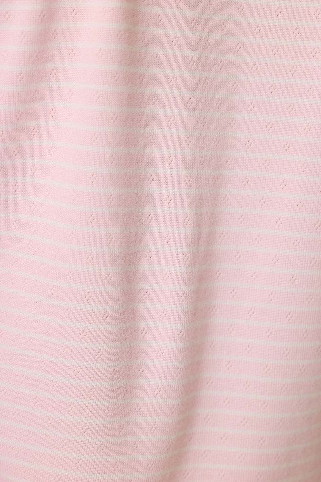 The Pretty Stripes Tender Pink Pointelle  fabric is light pink with subtle horizontal white stripes and delicate dotted patterns, offering a soft texture perfect for comfortable loungewear.