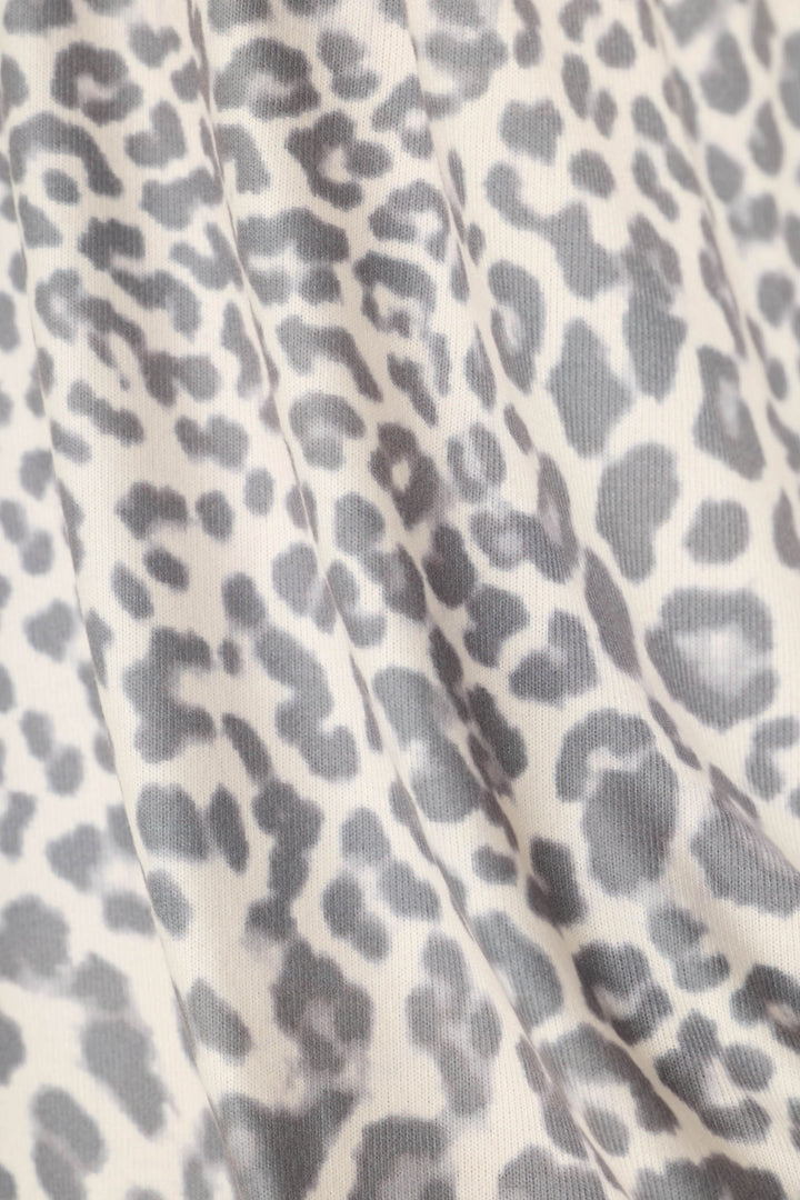 Close-up of a leopard print fabric with gray spots on a warm off-white background.