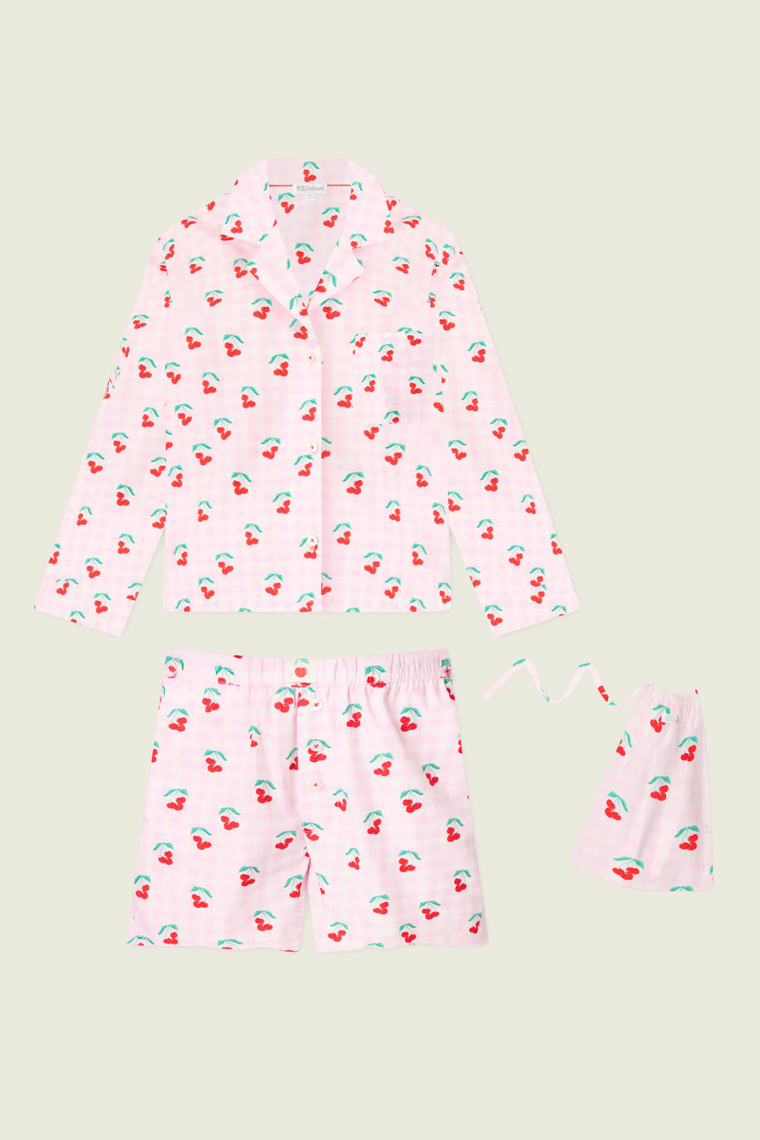 The P.J. Salvage Afterparty Poplin Oh Cherry Short PJ Set features a powder pink cotton poplin, cherry-printed long-sleeve button-up shirt, shorts, and a matching drawstring bag, all shown against a light background.