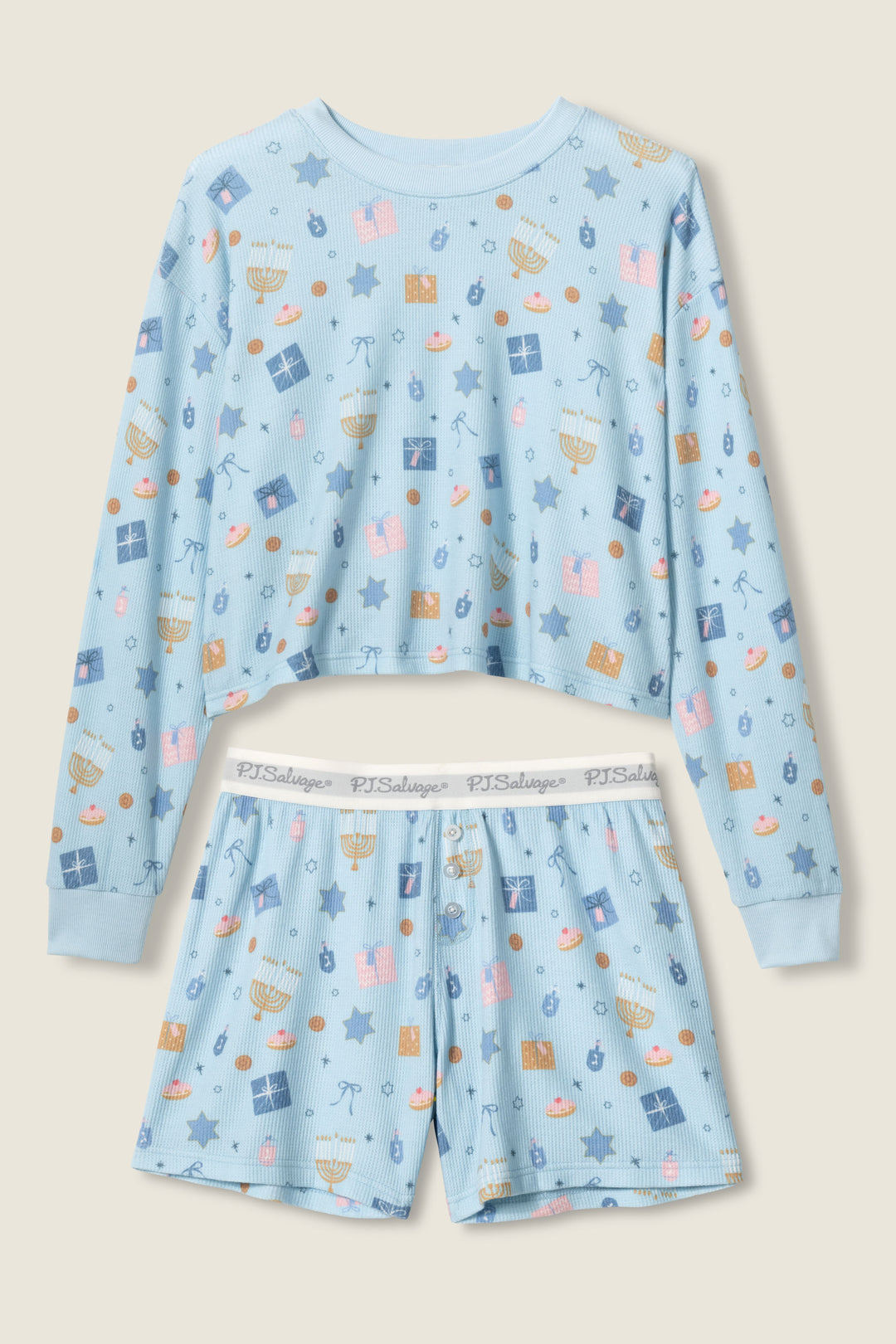 The STARS PJ SET BOYFRIEND BOXER SHORT GIFT SET by P.J. Salvage is a light blue, long-sleeve crop top and shorts pajama set with playful Hanukkah-themed prints like menorahs, dreidels, gifts, Stars of David, and sufganiyot.