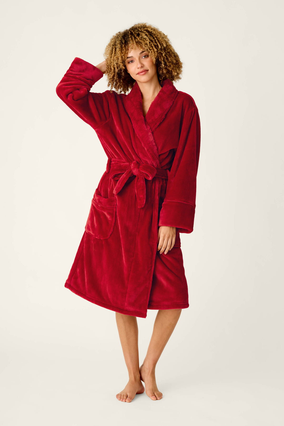 A woman wearing a cozy, plush red Luxe Plush Red Robe by P.J. Salvage with a shawl collar and tie waist.