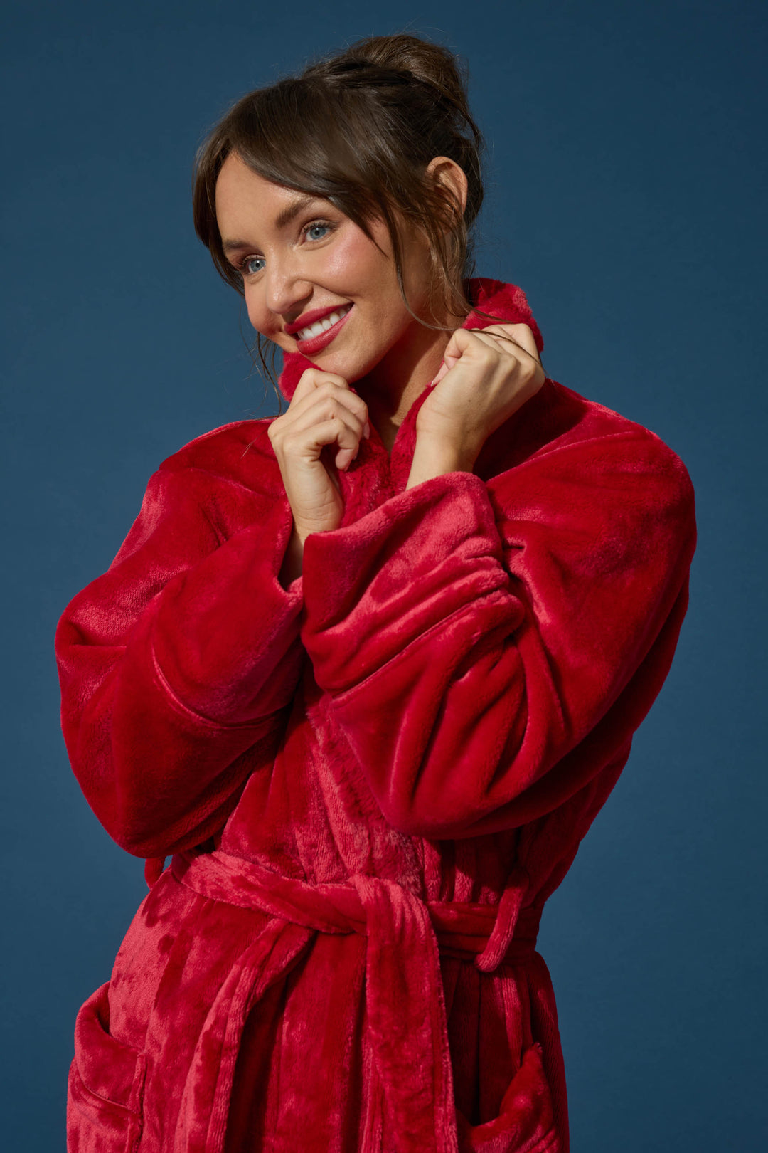 A smiling woman wearing a cozy, plush red Luxe Plush Red Robe by P.J. Salvage with a tie waist.