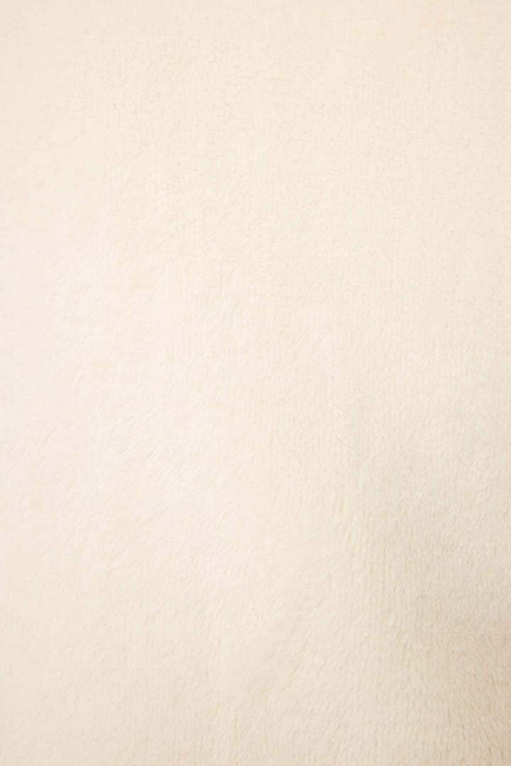 A close-up of the P.J. Salvage Luxe Plush Solid Ivory Robe reveals a smooth, light beige surface with a soft, fuzzy texture and even color, showcasing the robe's luxurious feel without visible patterns or prominent details.
