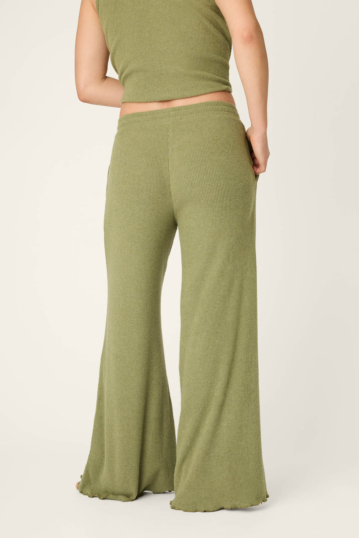 A person faces away, wearing P.J. Salvage Olive You Forever Lounge Pants in olive green with a matching ribbed sleeveless top. The outfit is soft and comfortable with loose, flowy pants and a cropped top against a light plain background.