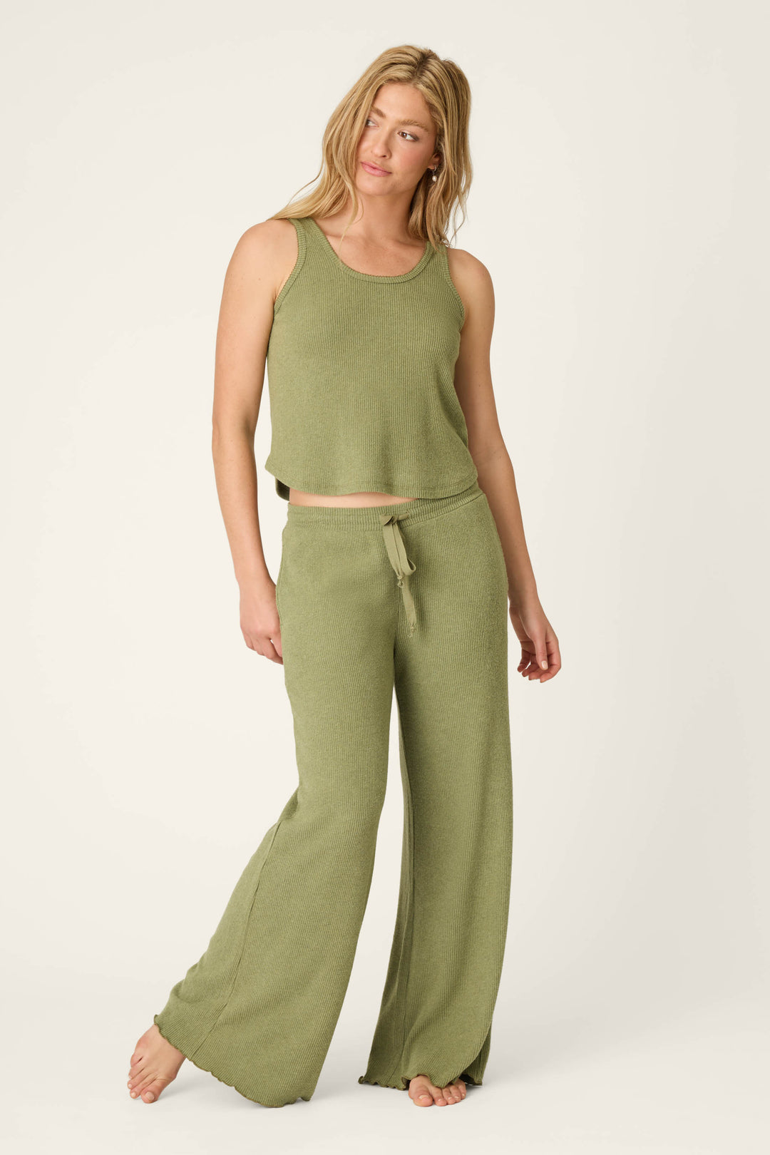 A woman stands barefoot against a plain background, wearing the P.J. Salvage Olive You Forever Tank Top and matching wide-leg pants with a drawstring waist, looking relaxed as she gazes slightly to the side.