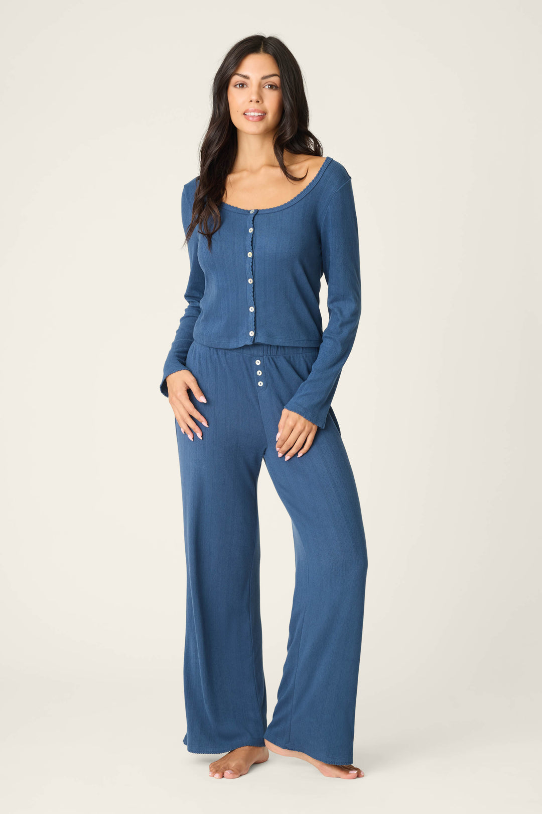 A person stands barefoot against a plain light background, wearing the P.J. Salvage Pointelle Essentials Deep Sea Cardigan as part of a cozy lounge set.