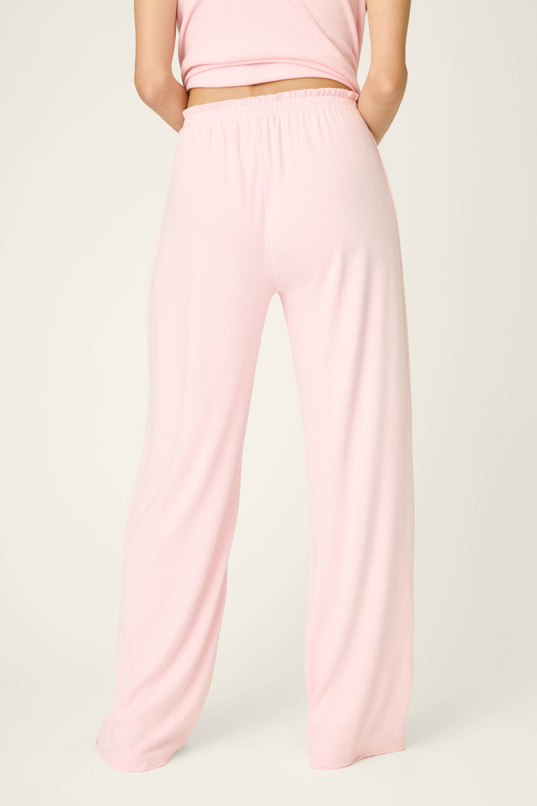 A person stands with their back to the camera against a plain light background, wearing P.J. Salvage Pointelle Essentials Ballet Pink Open Leg Pants and a matching sleeveless top.