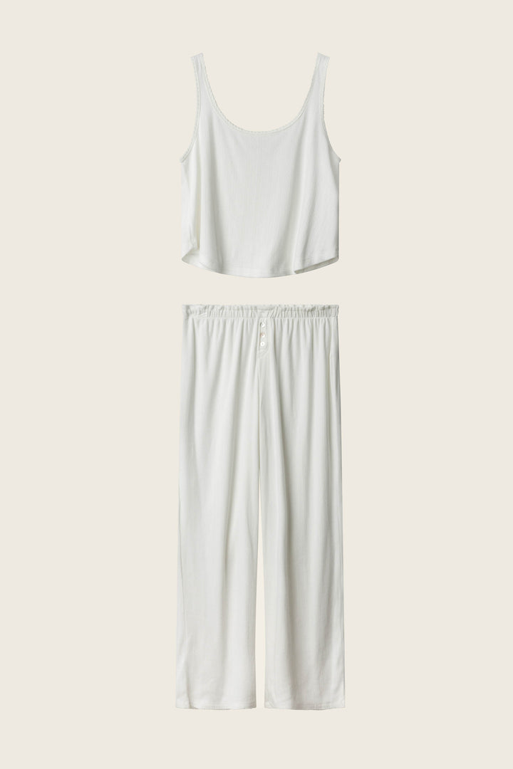 The Pointelle Essentials Ivory PJ Set by P.J. Salvage features a sleeveless cropped tank and wide-leg, elastic-waist pants, both in white, displayed on a cream background.