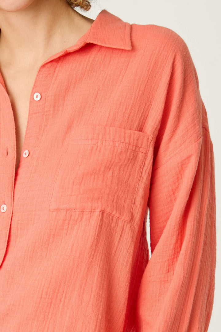 A textured hot coral-colored fabric with visible detailing, shown against a plain light background.