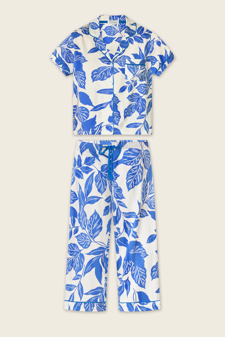 The Whimsy Sapphire Garden Cropped PJ Set by P.J. Salvage features a short-sleeve, button-up top and ankle-length, cuffed drawstring pants, both with a blue botanical leaf print on white.
