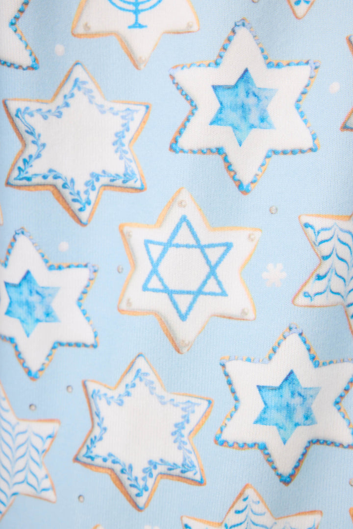 The HANUKKAH PJ SET YOU HAD ME AT SHALOM by P.J. Salvage features a festive pattern of blue and white Hanukkah star-shaped cookies, some with the Star of David, set on a light blue background.