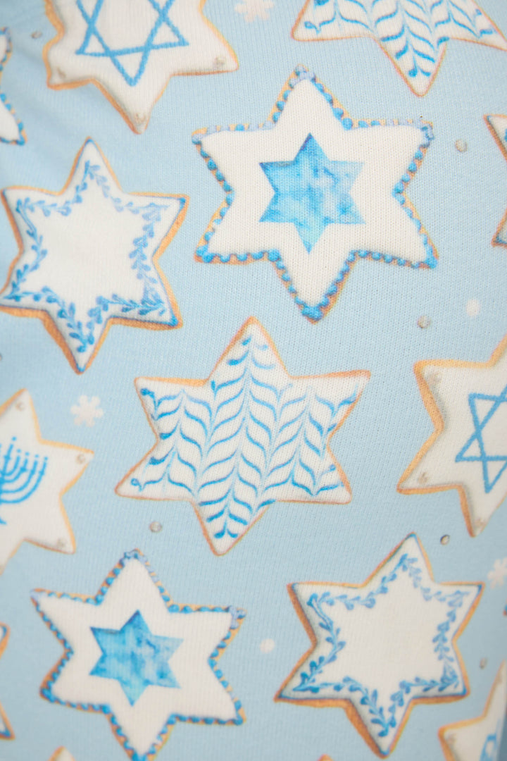 A close-up of P.J. Salvage’s HANUKKAH BANDED PANT YOU HAD ME AT SHALOM, featuring white and blue Hanukkah-themed designs like the Star of David and menorahs on a light blue background.