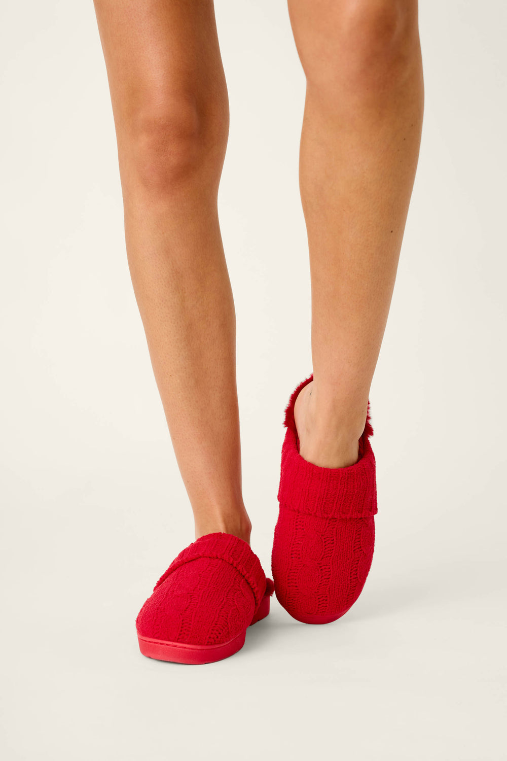 A pair of cozy red P.J. Salvage Cozy Chenille Cable Knit Red Slippers on a person’s feet.