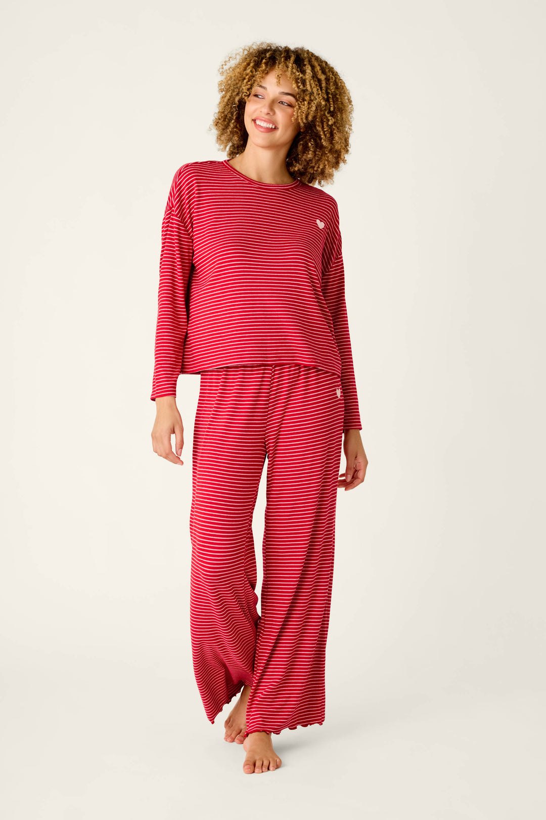 A person wearing an Icon Stripes Red Long Sleeve PJ Set, consisting of a red striped long-sleeved shirt and matching wide-leg pants.