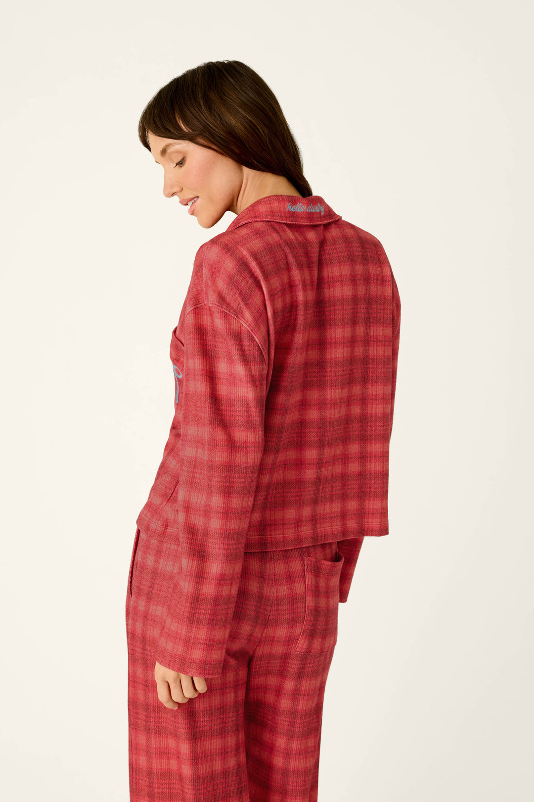 A woman wearing a P.J. Salvage Mad for Plaid Long Sleeve Notch Collar Top and matching pants, featuring hello darling embroidered on the notch collar.