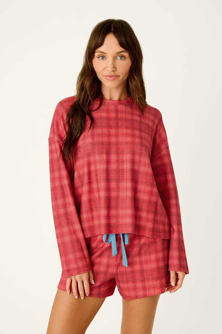 A woman wearing a P.J. Salvage Mad for Plaid Long Sleeve Top and matching shorts with a blue drawstring.
