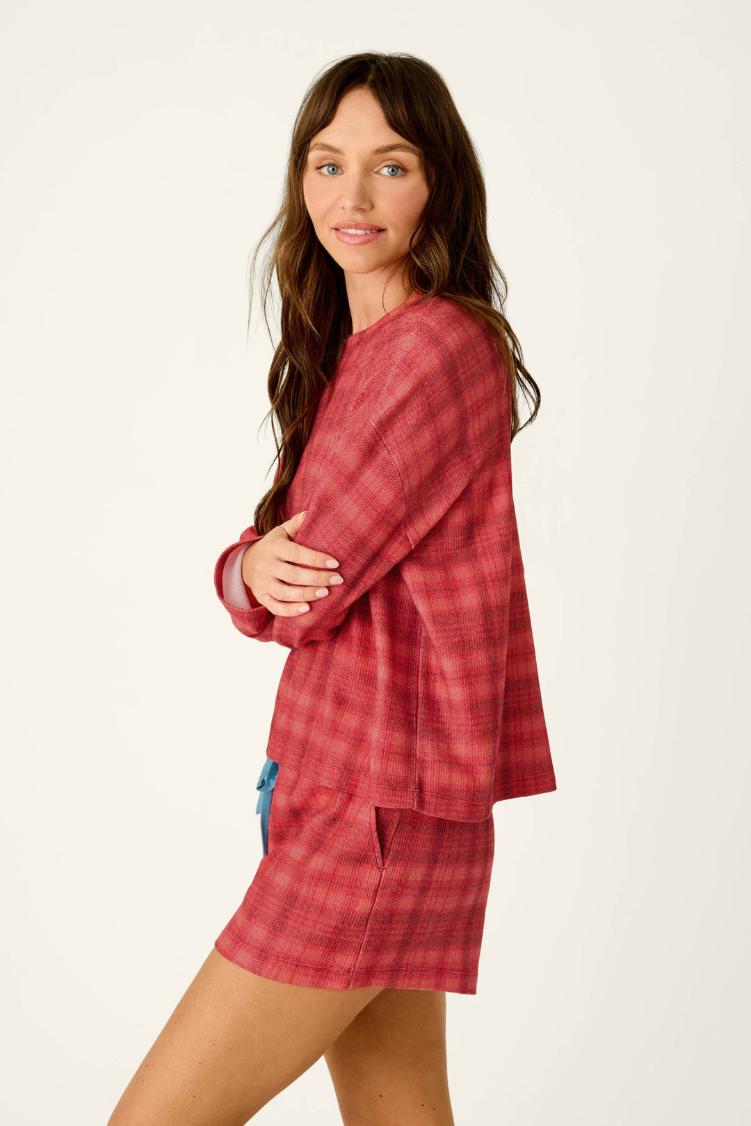 A woman with her arms crossed wears a Mad for Plaid Long Sleeve Top with matching plaid shorts.