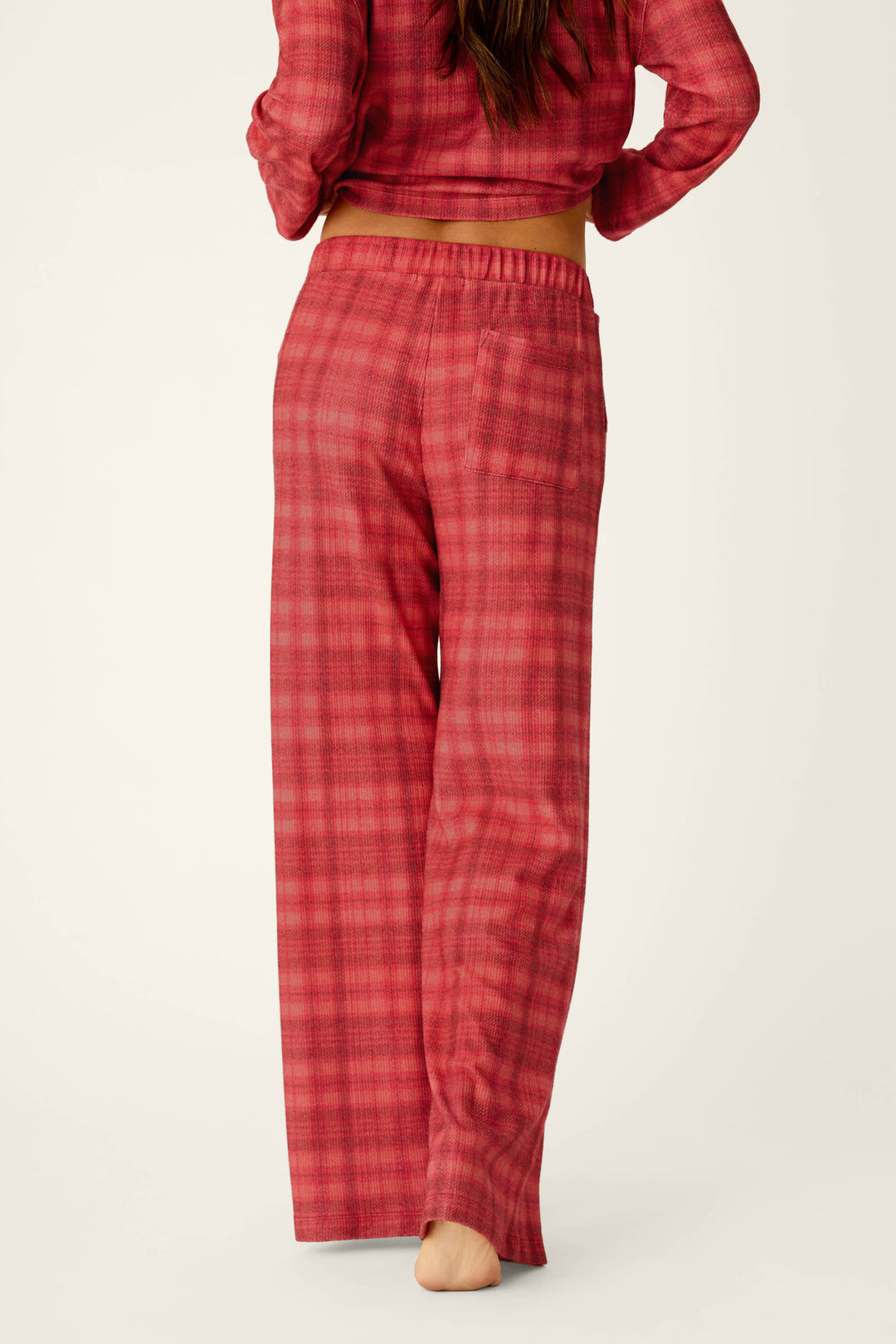 A person seen from behind wears a matching red plaid long-sleeved top and Mad for Plaid Pajama Pants for cozy sleepwear.