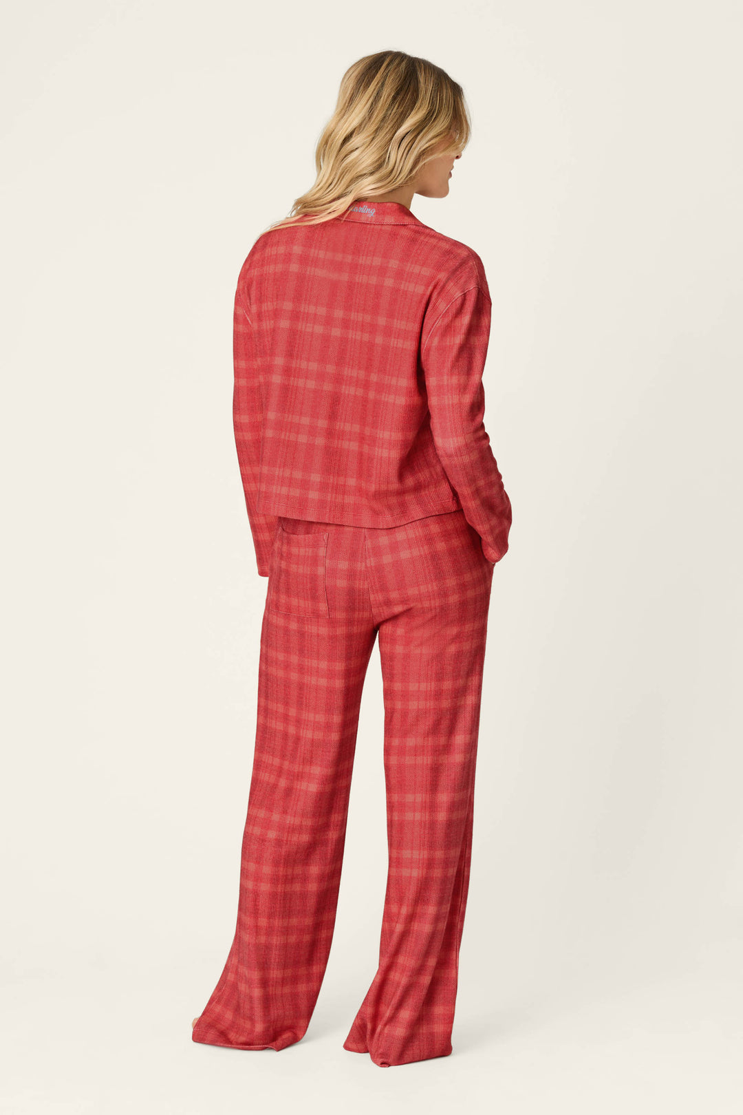 A person seen from behind wearing a red plaid Mad for Plaid Long Sleeve & Pants PJ Set by P.J. Salvage, featuring a long-sleeve top and matching wide-leg pants.
