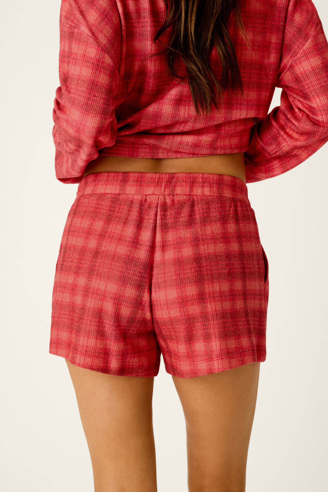Viewed from behind, a person wears soft, baby waffle knit Mad for Plaid Pajama Shorts and a matching long-sleeved top in red plaid.