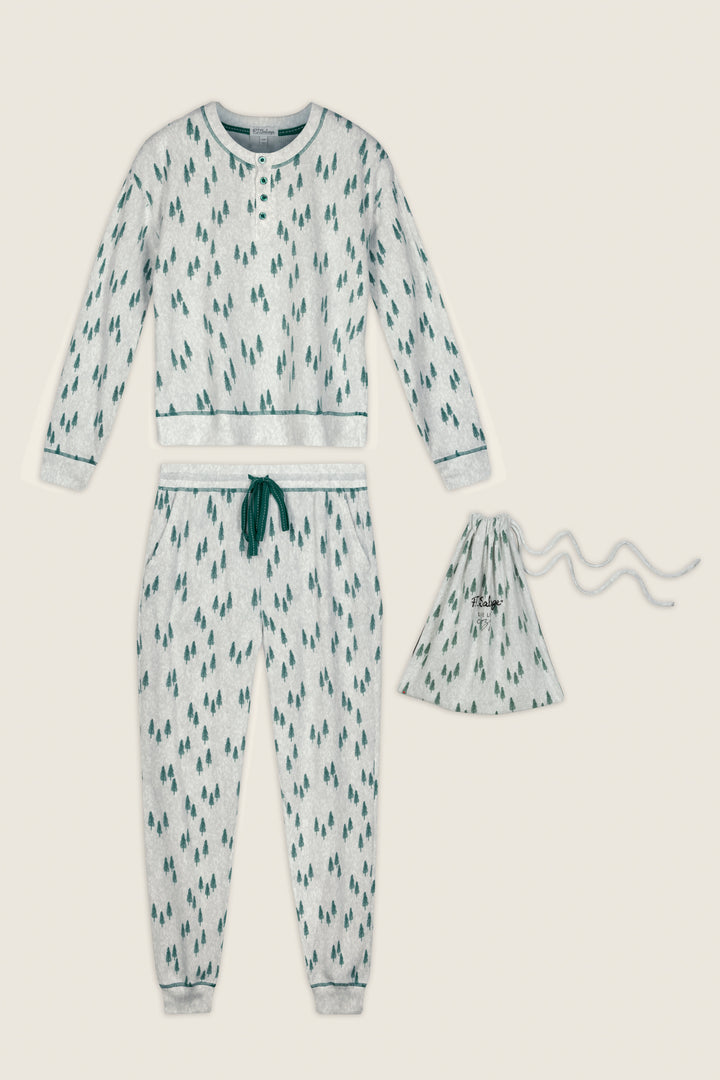 The P.J. Salvage Trees Print 3-Piece PJ Gift Set includes light grey pajamas adorned with small green tree patterns, featuring long sleeves and pants with green accents on the cuffs and waistband, and comes complete with a coordinating drawstring bag.