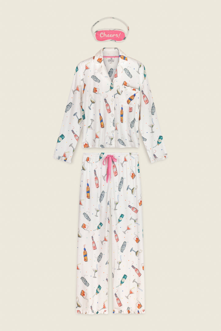 P.J. Salvage Sip Sip Sparkle Cocktail Charms Print 3-Piece PJ Set featuring ivory long-sleeved button-up pajamas, drawstring pants, and a Cheers! sleep mask, all adorned with colorful cocktail glasses and bottles.
