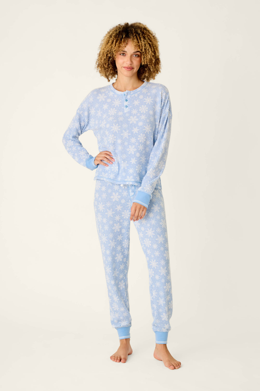 A woman wearing a light blue, long-sleeved Ski Jammie Classics Snowflake Print Long Sleeve PJ Set by P.J. Salvage with a white snowflake pattern.