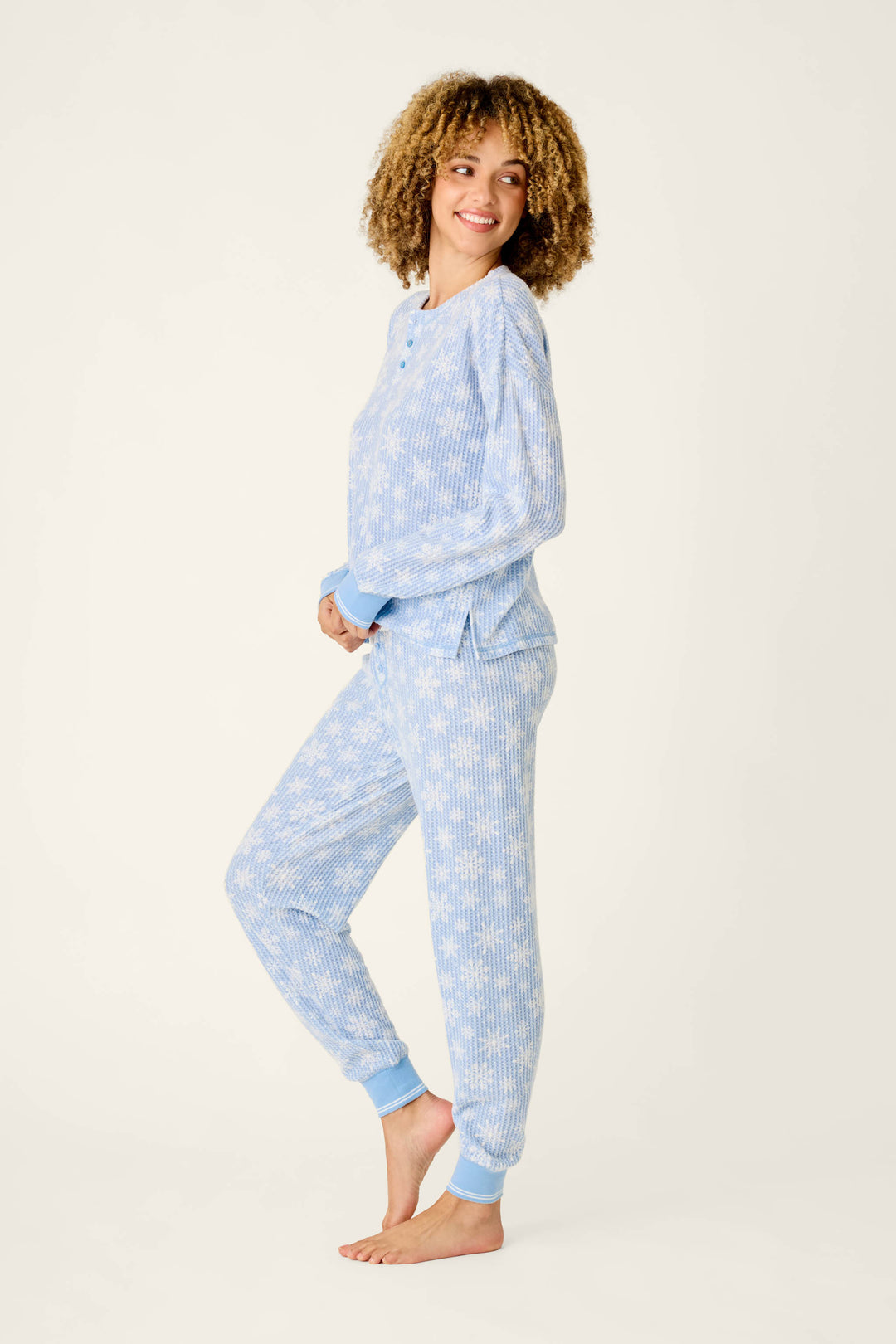 A woman wears a light blue, long-sleeved waffle-knit Ski Jammie Classics Snowflake Print Long Sleeve PJ Set by P.J. Salvage.