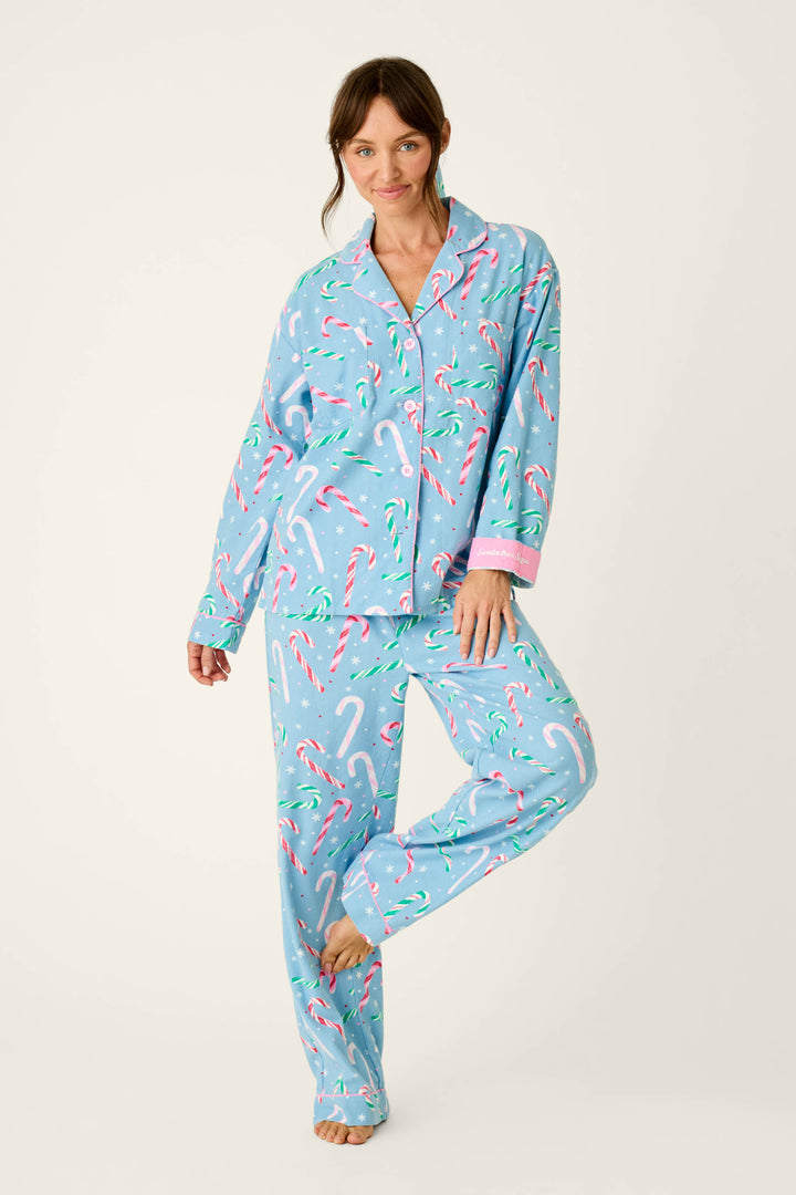 A woman wearing The Sweetest Season Candy Cane Print Flannel 3-Piece PJ Set in light blue with a pattern of candy canes, white snowflakes, and pink trim.