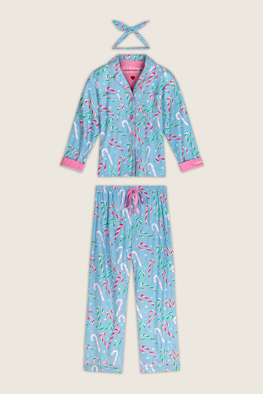 The Sweetest Season Candy Cane Print Flannel 3-Piece PJ Set featuring a long-sleeved button-down top, drawstring pants, and a headband in blue fabric with a red, white, and green candy cane and snowflake pattern, finished with pink trim.