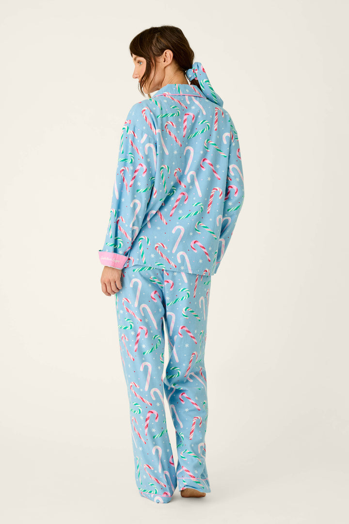 A person wearing The Sweetest Season Candy Cane Print Flannel 3-Piece PJ Set in light blue with a candy cane and snowflake print, complemented by a matching scrunchie.
