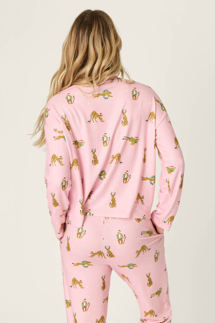 Back view of a person wearing a pink Very Merry Wild for the Holidays Long Sleeve Top and matching pants, featuring a repeating pattern of leopards wearing Santa hats and holiday wreaths.