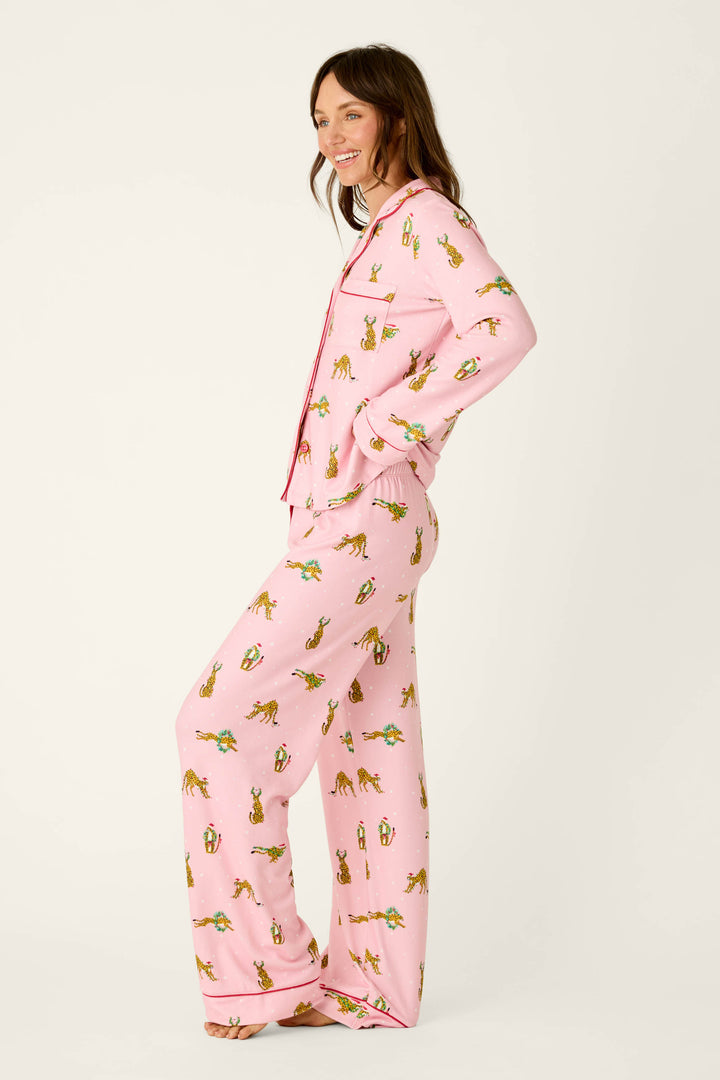 A woman wearing a P.J. Salvage Very Merry Wild for the Holidays 3-Piece PJ Set, featuring a festive leopard print with pink long-sleeved pajamas and red piping.