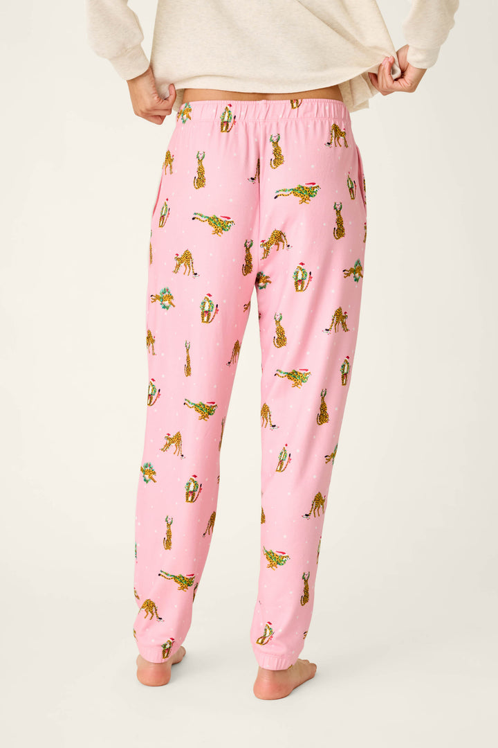 Person wearing pink P.J. Salvage Very Merry Wild for the Holidays Jogger Pants in a butter jersey fabric featuring a holiday-themed leopard print.