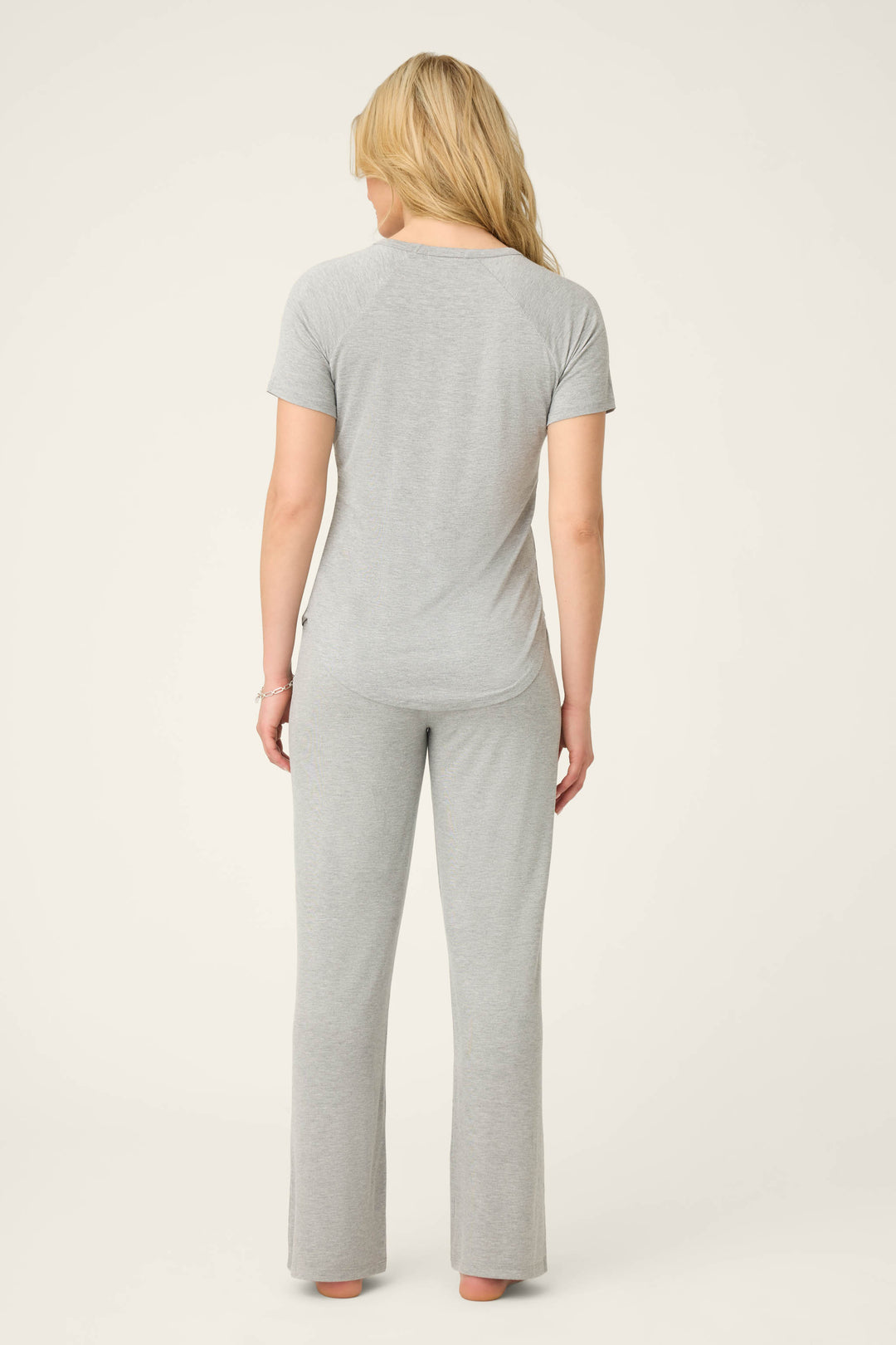 A person with long blonde hair stands barefoot, facing away from the camera, wearing the P.J. Salvage Modal Basics Heather Grey PJ Set against a plain light background.