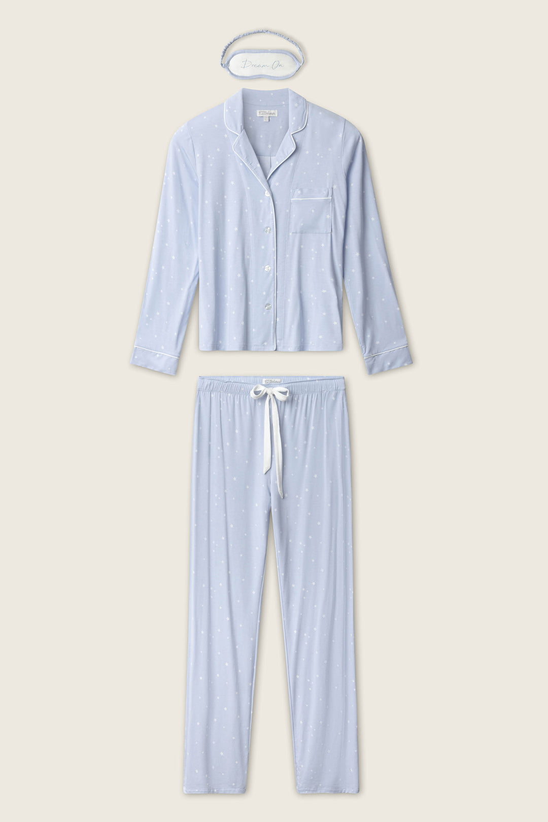 The P.J. Salvage Modal Basics Star Print 3-Piece PJ Set features a light blue, star-print long-sleeve button-up top, matching pants with a white drawstring, and a headband, all displayed flat on a beige background.