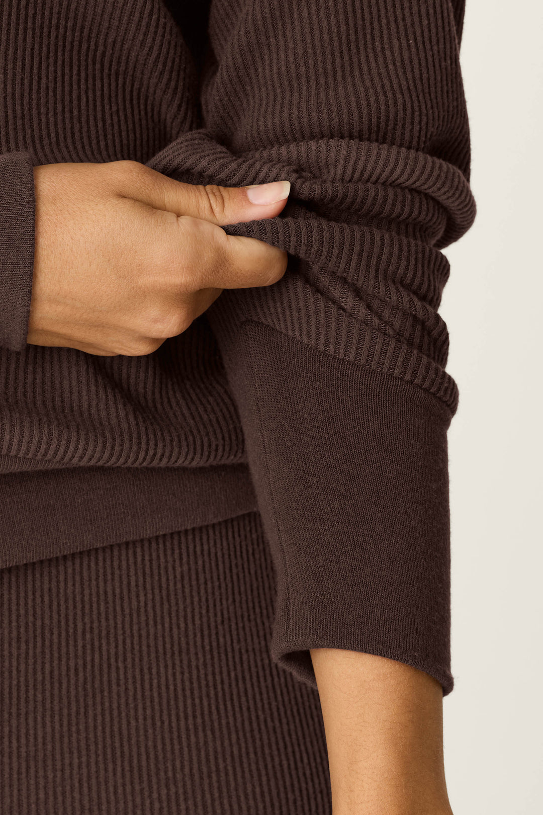 A person wearing the P.J. Salvage Textured Essentials Chocolate Brown Long Sleeve Top is pulling up one sleeve with their left hand, revealing part of their forearm.