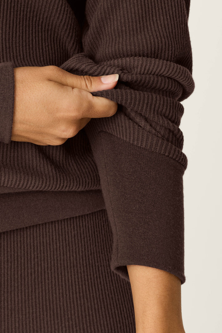 A person wearing the P.J. Salvage Textured Essentials Chocolate Brown Long Sleeve Top is pulling up one sleeve with their left hand, revealing part of their forearm.