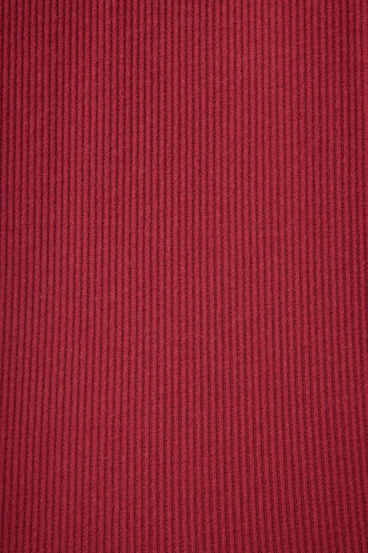Close-up of the Textured Essentials Long Sleeve Top in Port by P.J. Salvage, featuring red ribbed fabric with vertical lines and a subtly raised pattern across the surface.