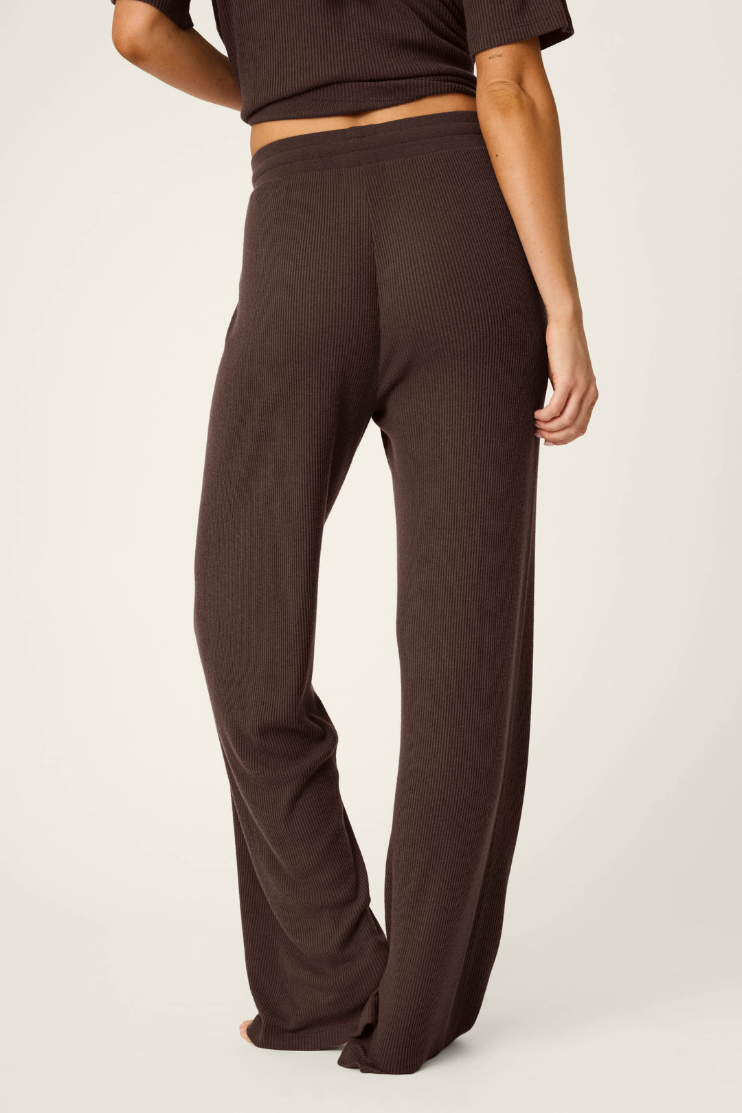 A person wearing the P.J. Salvage Textured Essentials Chocolate Brown Lounge Pants and a matching top, barefoot, stands with their back to the camera against a plain light background.