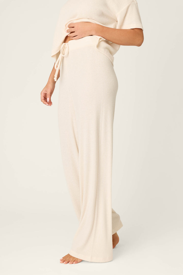 A person wearing P.J. Salvage Textured Essentials Stone Open Leg Pants, styled barefoot with a matching short-sleeve knit top and tie belt, stands against a plain background.