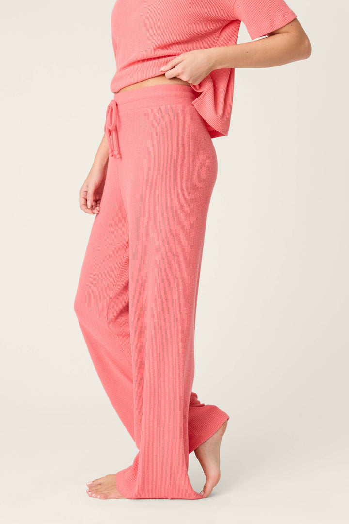 A person stands barefoot in P.J. Salvage Textured Essentials Sunset Rose Open Leg Pants, paired with a matching short-sleeve top. The side view, from shoulders to feet, is set against an off-white background.