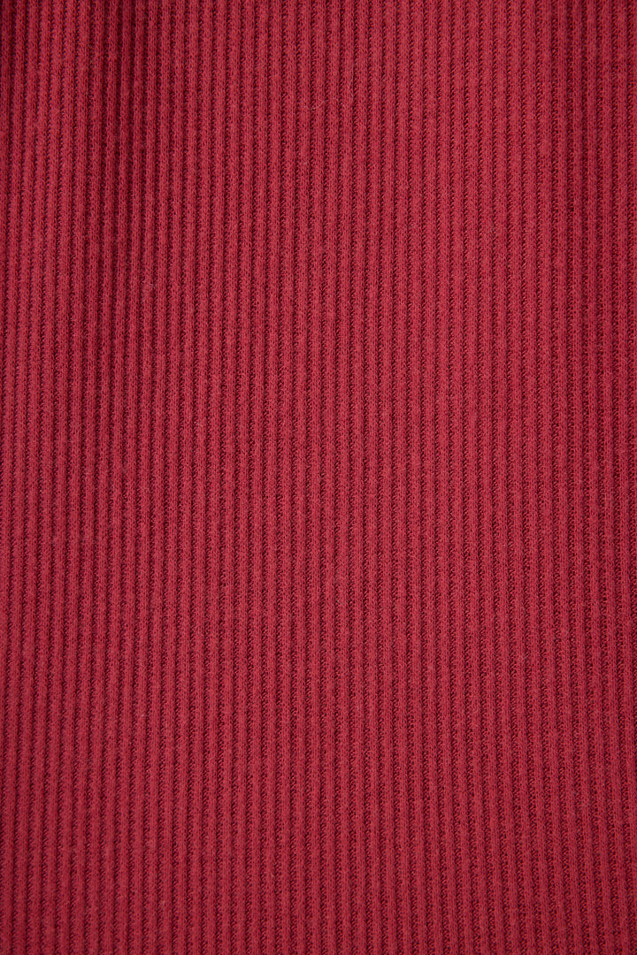 Close-up of P.J. Salvage Textured Essentials Banded Pants in Port, showing the soft red ribbed fabric with evenly spaced vertical textured lines across the surface.