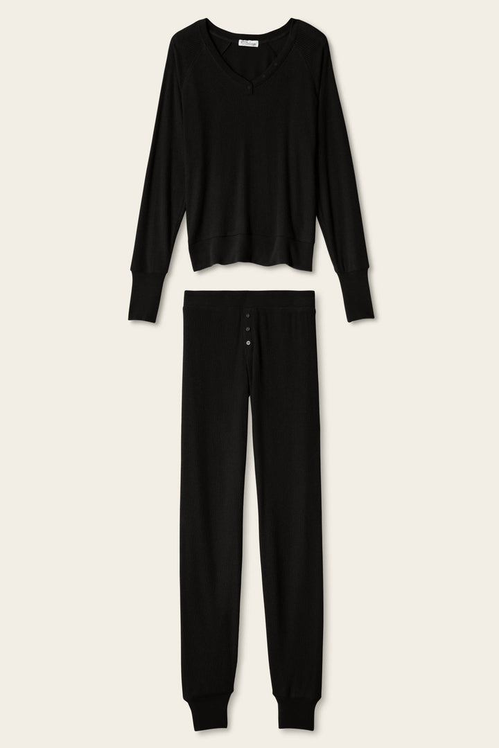 The P.J. Salvage Textured Essentials Black Lounge Set features a matching ensemble of soft, ribbed fabric, including a relaxed V-neck long-sleeve top and button-fly pants, displayed on a plain light background.
