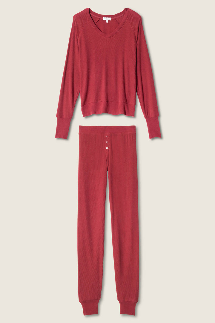 The P.J. Salvage Textured Essentials PJ Set—red long-sleeve V-neck top and long pants with a button fly—is displayed flat on a light background.