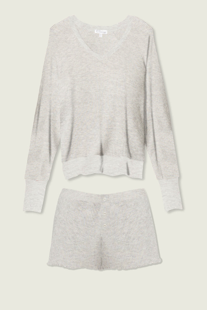 The P.J. Salvage Textured Essentials Heather Grey Short Lounge Set features a light gray ribbed knit, with a long-sleeve V-neck top and button-detailed shorts, shown laid flat on a light background.
