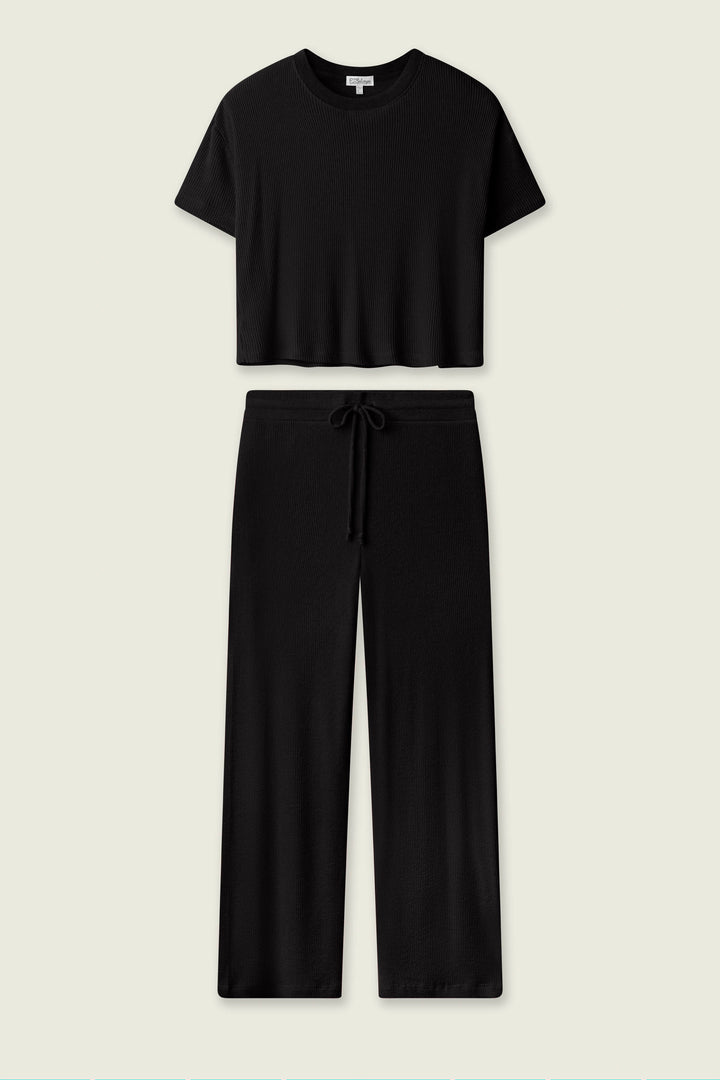The P.J. Salvage Textured Essentials Black Long PJ Set features a short-sleeve cropped crewneck top and wide-leg drawstring pants, shown on a plain light background—ideal cozy loungewear for stylish relaxation.